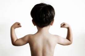 A boy pictured from behind with both arms up showing his muscles.